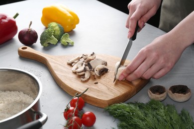 Photo of Healthy food. Woman cutting champignon at grey table, closeup