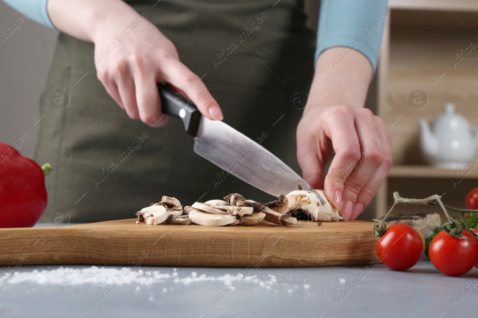 Photo of Healthy food. Woman cutting champignon at grey table, closeup