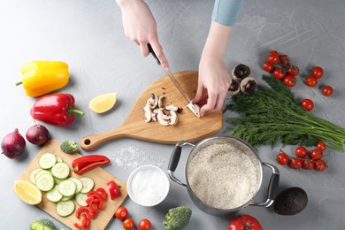 Photo of Healthy food. Woman cutting champignon at grey table, top view