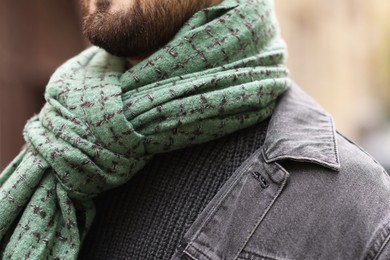 Photo of Man in warm scarf on city street, closeup