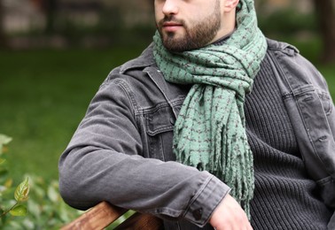 Man in warm scarf on city street, closeup