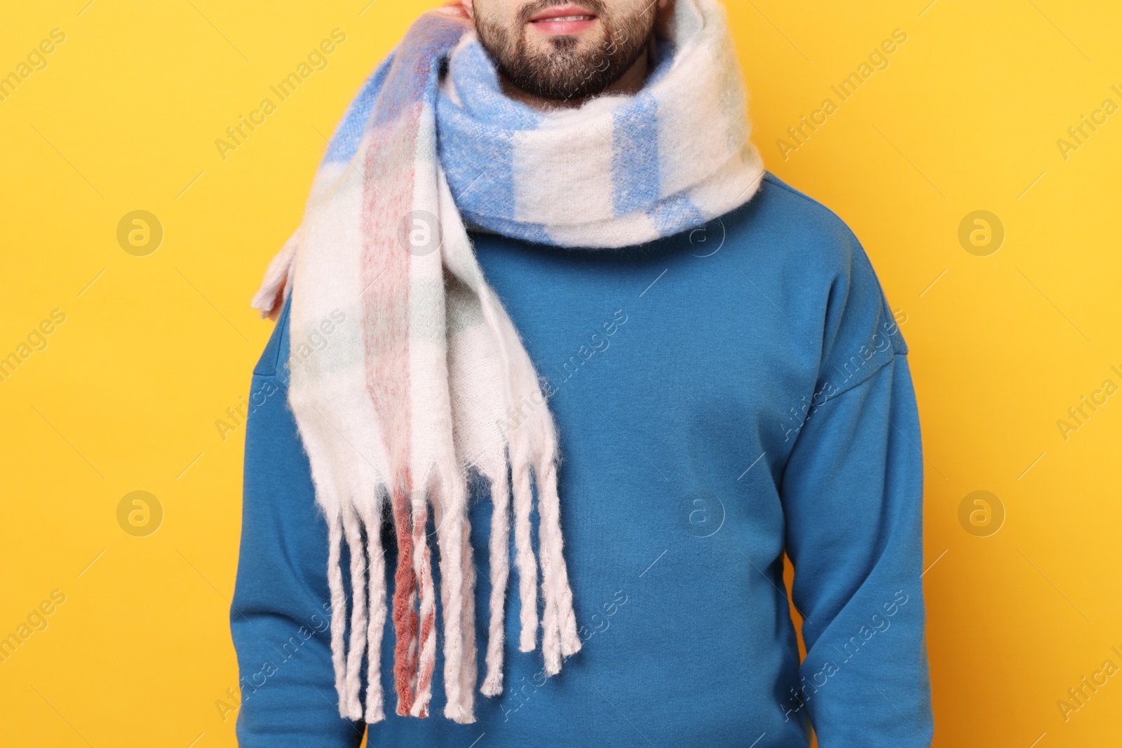 Photo of Man in warm scarf on yellow background, closeup