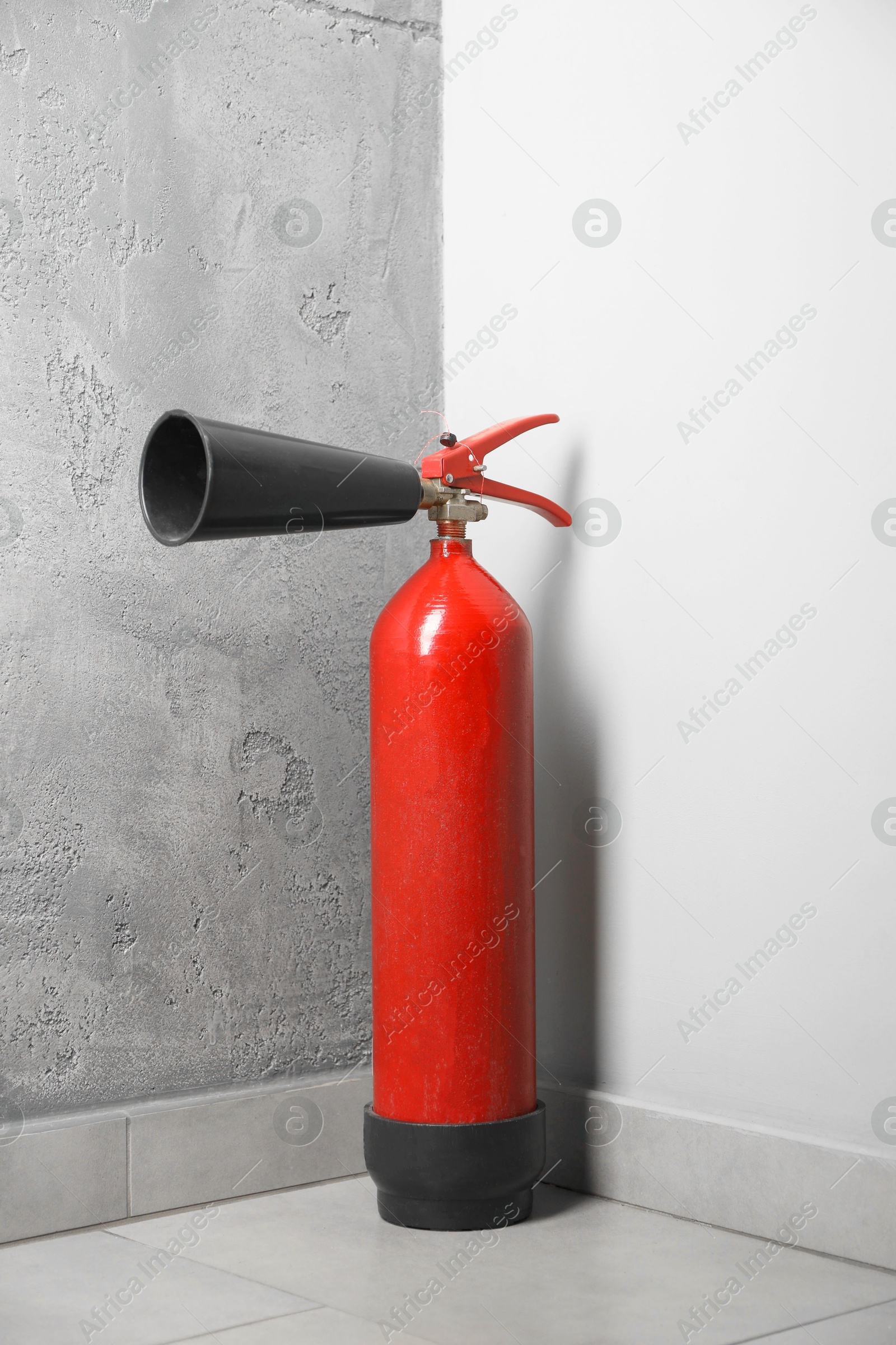 Photo of Fire extinguisher on floor near grey wall indoors