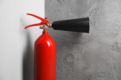 Photo of One fire extinguisher near grey wall indoors