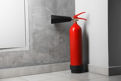 Photo of Fire extinguisher on floor near grey wall indoors