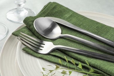 Stylish setting with cutlery, leaves and plates on table, closeup