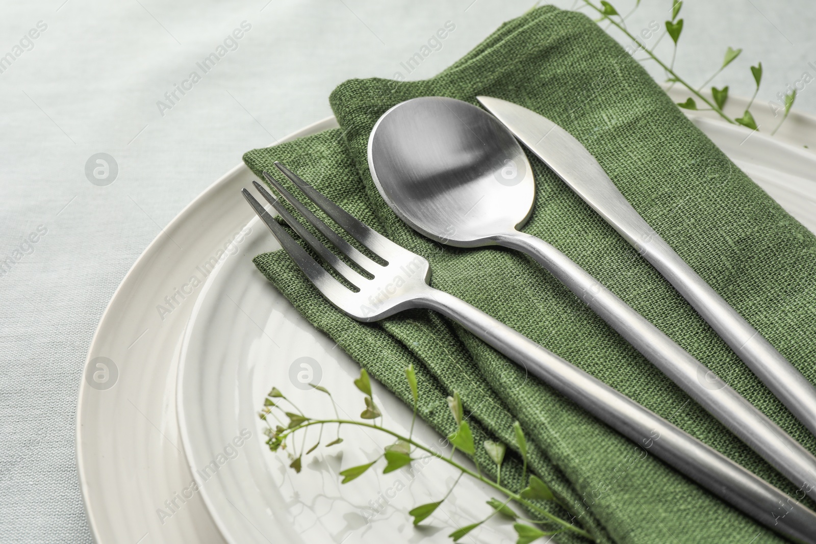 Photo of Stylish setting with cutlery, leaves and plates on table, closeup