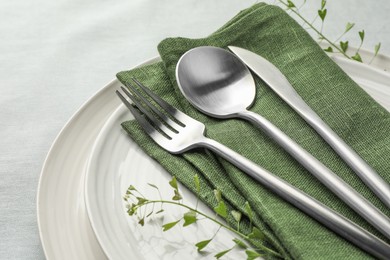 Photo of Stylish setting with cutlery, leaves and plates on table, closeup