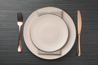 Photo of Stylish setting with cutlery and plates on black wooden table, flat lay