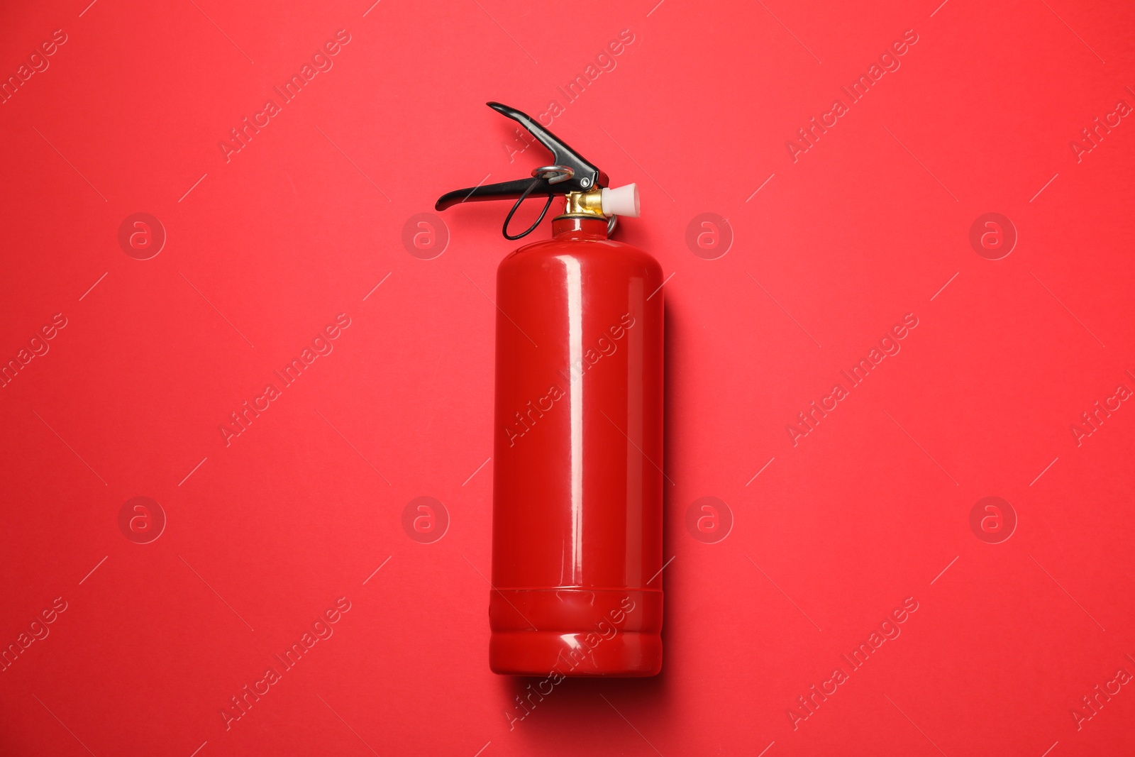 Photo of One fire extinguisher on red background, top view