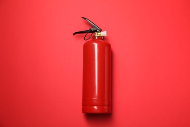 Photo of One fire extinguisher on red background, top view