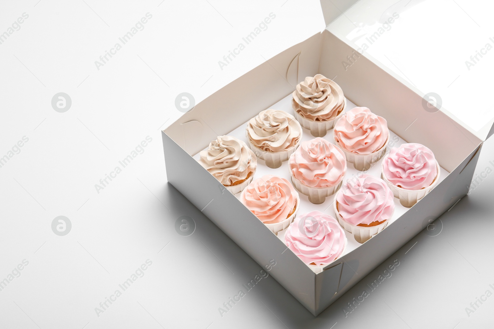 Photo of Tasty cupcakes in box on white background. Space for text