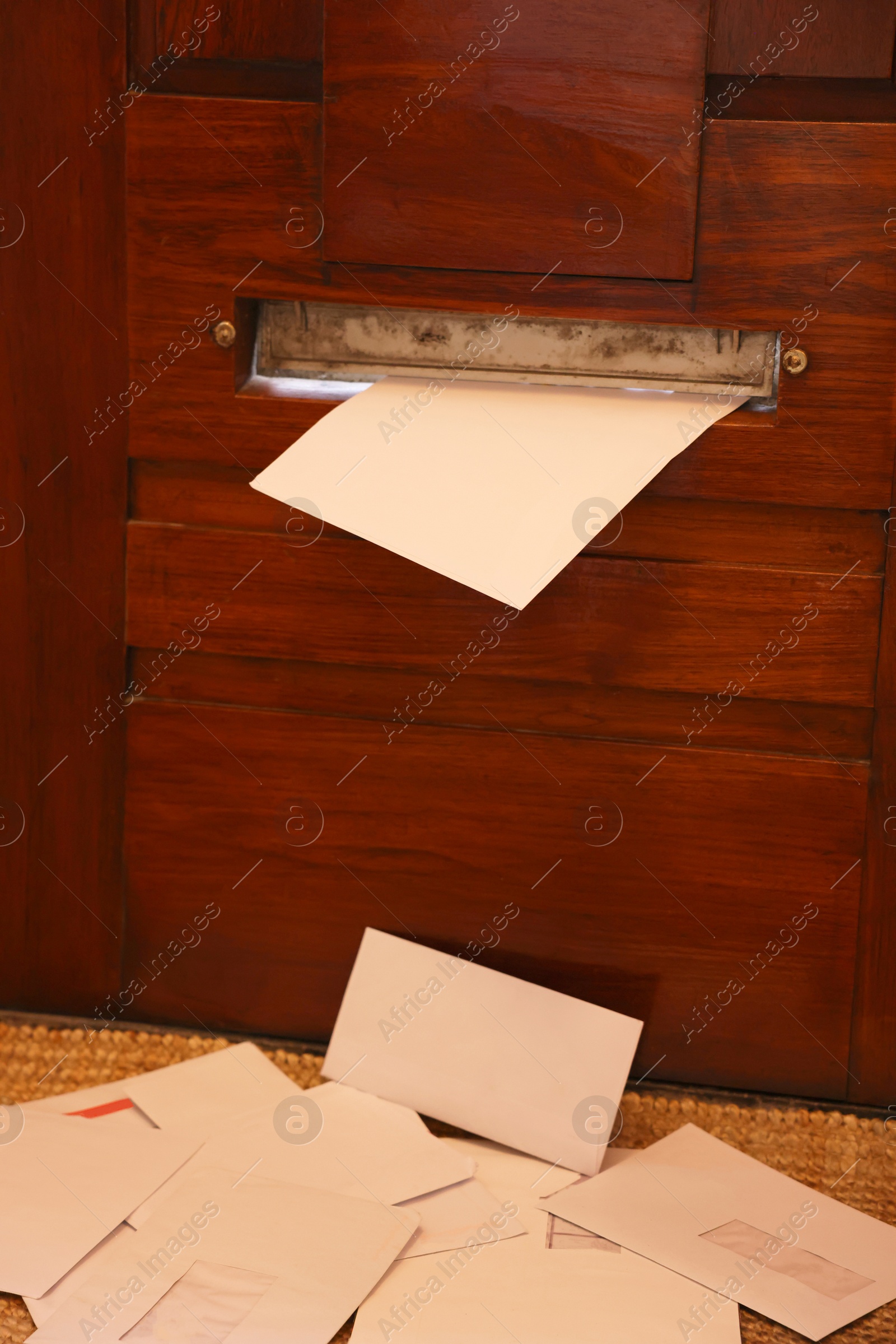 Photo of Wooden door with mail slot and many envelopes indoors