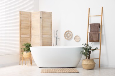 Folding screen, bathtub and green houseplants in bathroom