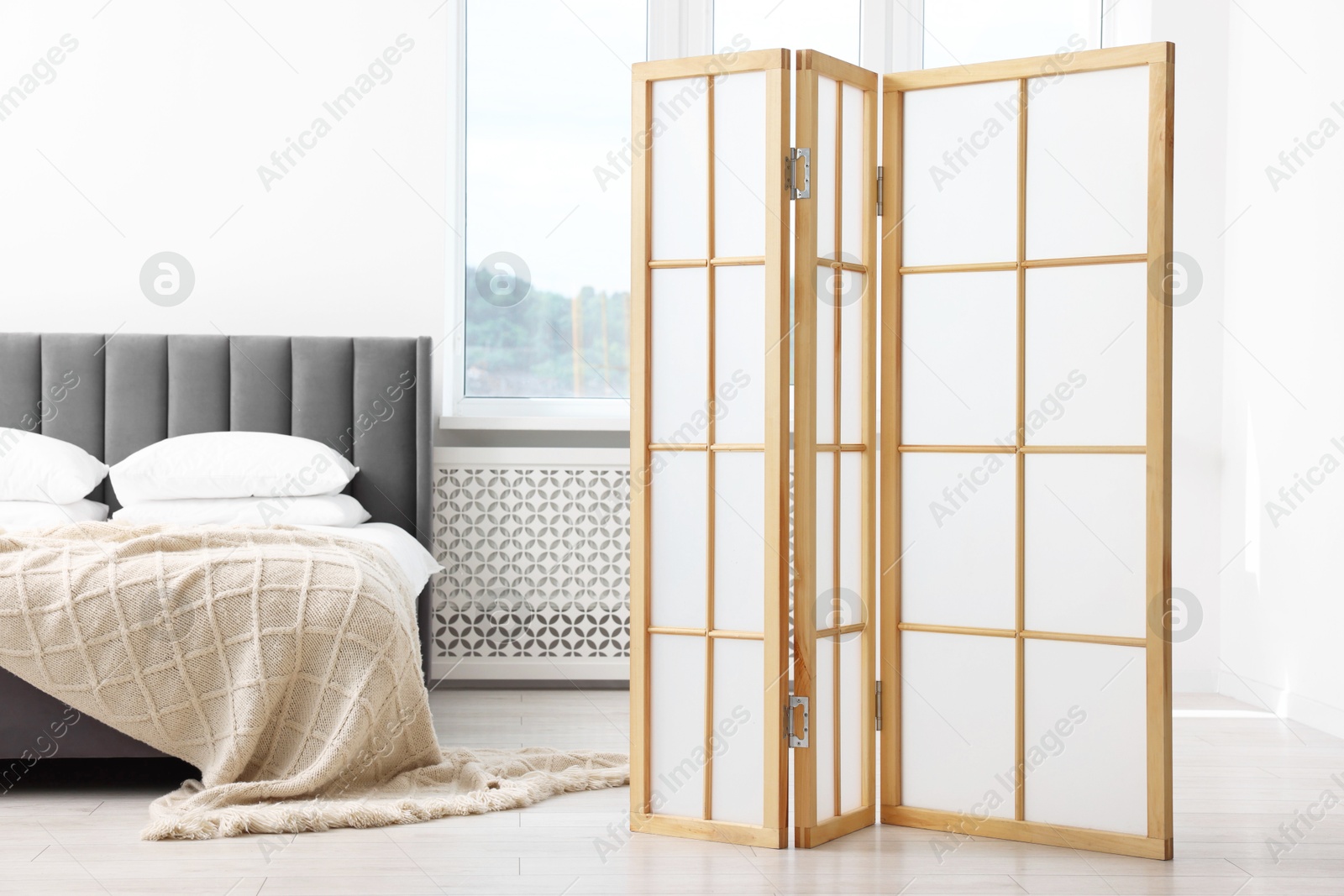 Photo of Folding screen and comfortable bed in bedroom