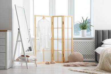 Photo of Folding screen, pouffe, mirror and bed in bedroom