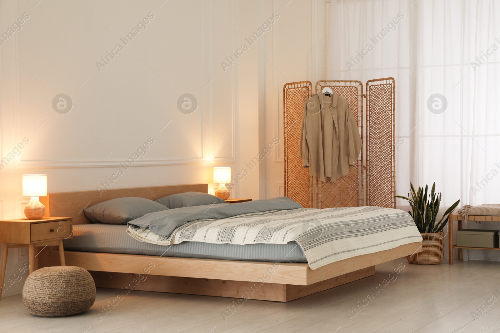 Photo of Stylish bedroom with double bed and folding screen. Modern interior