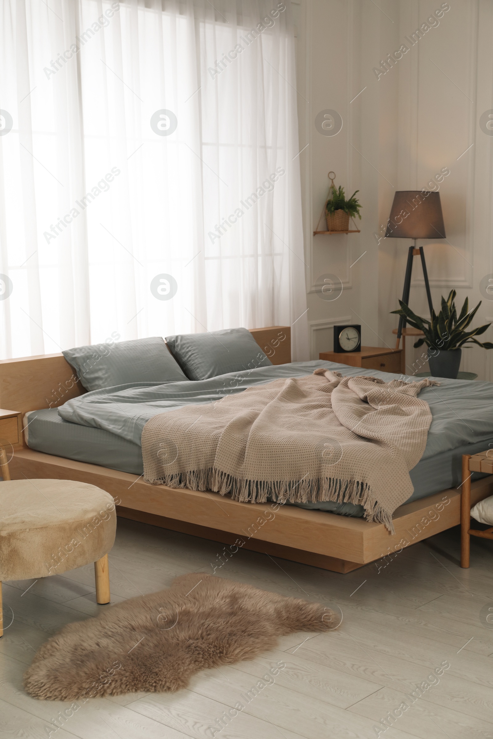 Photo of Stylish bedroom with double bed and beautiful green houseplants. Modern interior