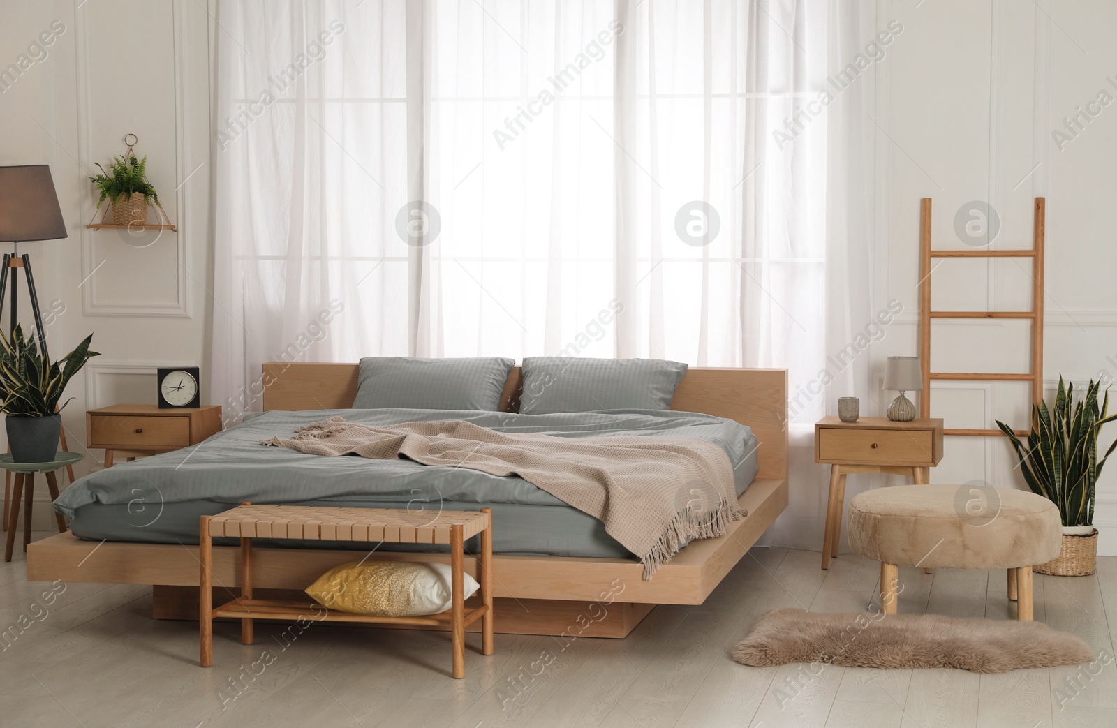 Photo of Stylish bedroom with double bed and beautiful green houseplants. Modern interior