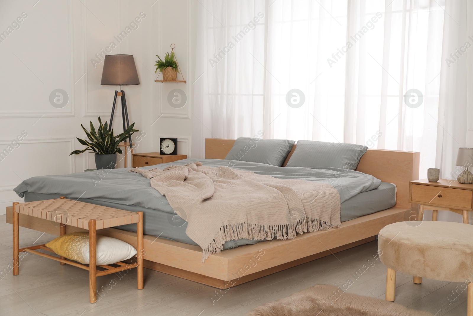 Photo of Stylish bedroom with double bed and beautiful green houseplants. Modern interior