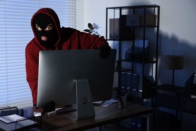 Photo of Thief stealing computer monitor in office at night. Burglary