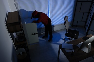 Photo of Thief looking for money in office at night, above view. Burglary