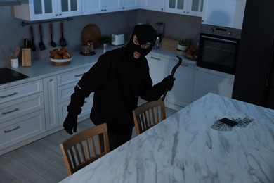 Thief in balaclava with crowbar entered foreign house for stealing. Burglary