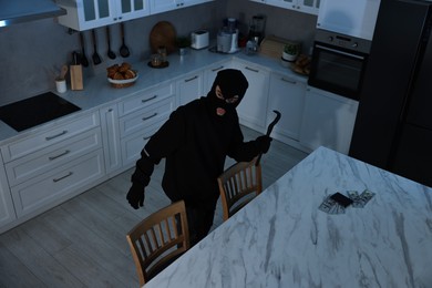 Photo of Thief in balaclava with crowbar entered foreign house for stealing, above view. Burglary
