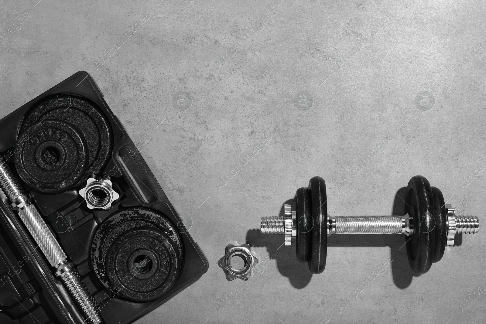 Photo of Barbell and parts of one on grey floor, flat lay. Space for text