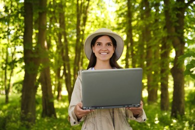 Photo of Forester with laptop examining plants in forest