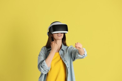 Photo of Smiling woman using virtual reality headset on yellow background