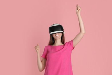 Photo of Smiling woman using virtual reality headset on pink background