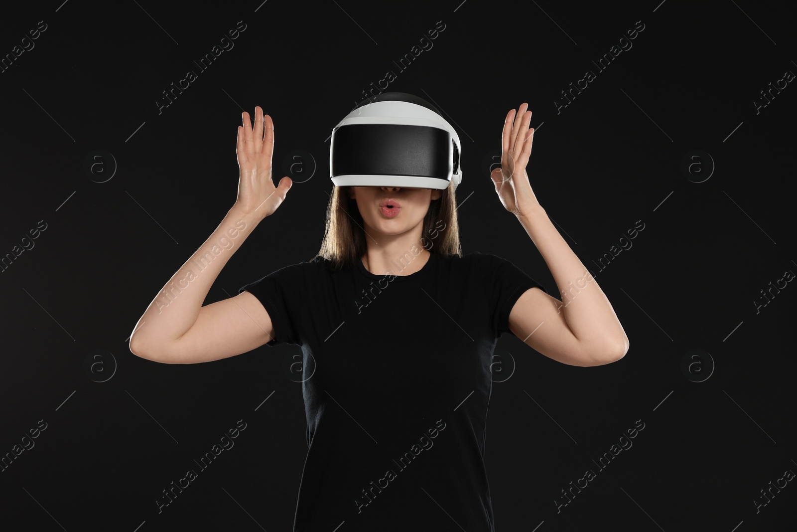 Photo of Surprised woman using virtual reality headset on black background