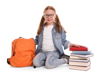 Smiling little girl with stack of books and backpack on white background