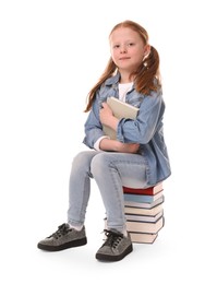 Cute little girl sitting on stack of books against white background