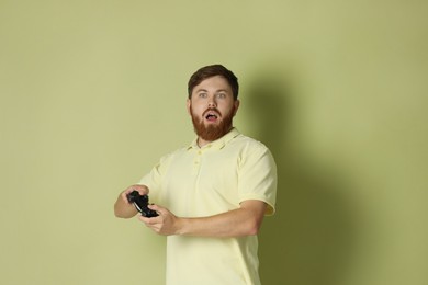 Photo of Surprised man with game controller on pale green background