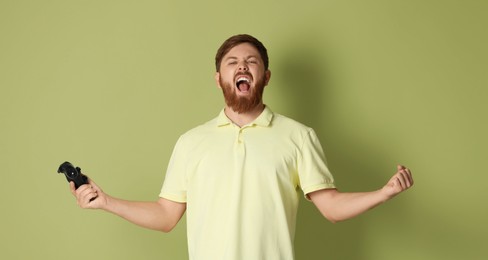 Photo of Emotional man with game controller on pale green background