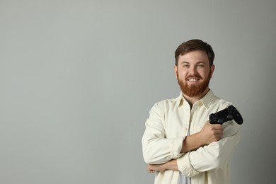 Photo of Smiling man with game controller on grey background. Space for text