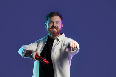 Photo of Happy man with game controller on dark blue background