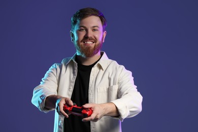Photo of Happy man playing video game with controller on dark blue background