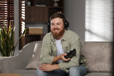 Happy man in headphones with game controller at home