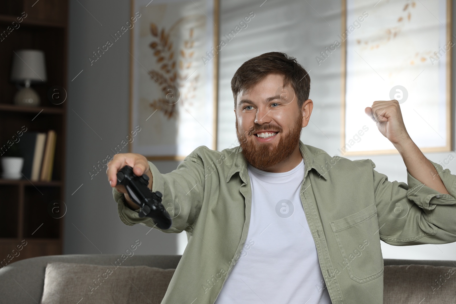 Photo of Happy man with game controller at home