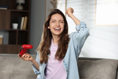 Photo of Happy woman playing video game with controller at home