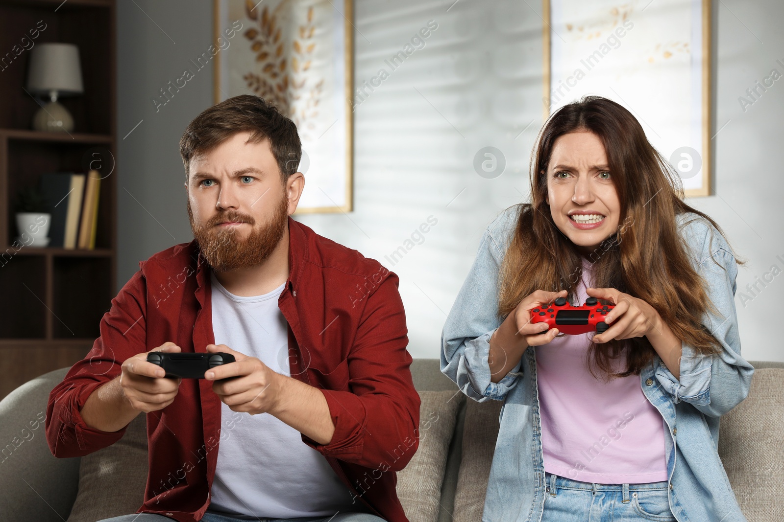 Photo of Couple playing video game with controllers at home