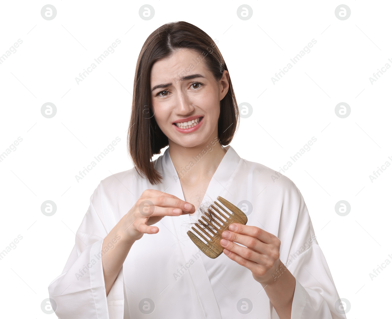 Photo of Emotional woman taking her lost hair from comb on white background. Alopecia problem