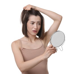 Sad woman with hair loss problem looking at mirror on white background