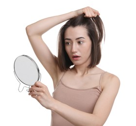 Sad woman with hair loss problem looking at mirror on white background