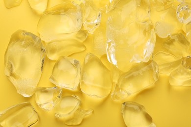 Pieces of crushed ice on yellow background, top view