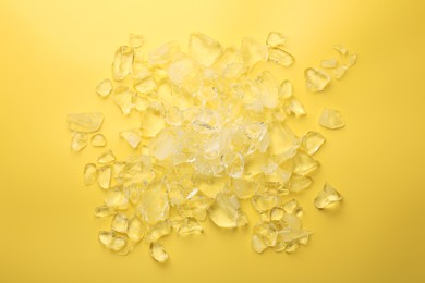 Photo of Pieces of crushed ice on yellow background, top view