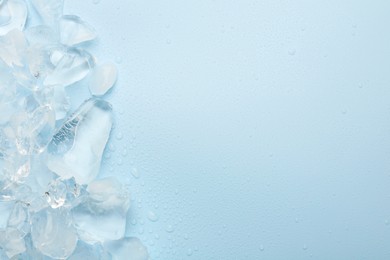 Photo of Pieces of crushed ice on light blue background, top view. Space for text